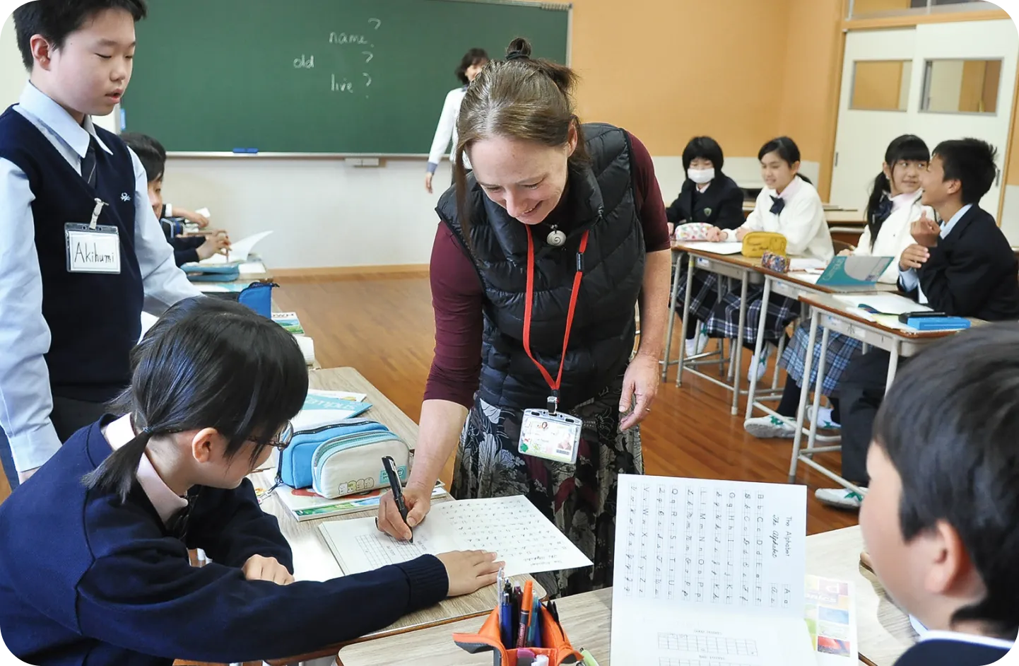 英語の授業で外国人教師が生徒に指導している様子